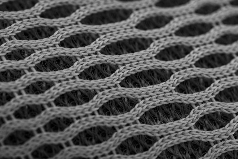 A detailed close-up of a grey knit nylon fabric creating an abstract geometric pattern, perfect for texture and design concepts.