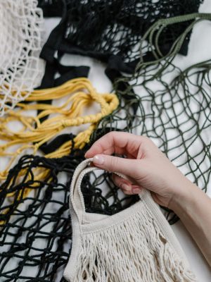 Close-up of a hand holding eco-friendly mesh bags in various colors emphasizing zero waste.