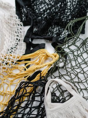 Close-up of various colored reusable mesh bags on white background.